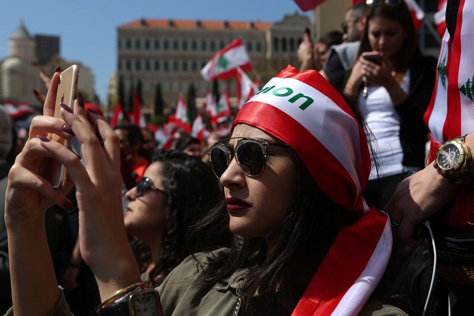 امرأة لبنانية تلتقط صورة خلال مظاهرة في وسط بيروت يوم 19 مارس 2017 ، ضد الضرائب التي أقرها البرلمان اللبناني مؤخراً.